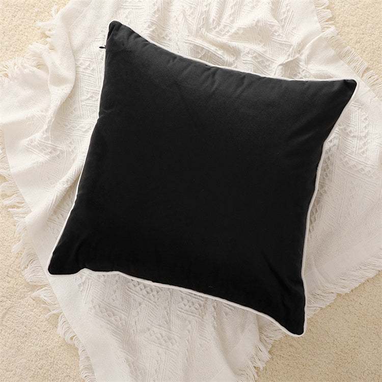 Black velvet cushion with white piping from a beautiful angle showing off a plump full look