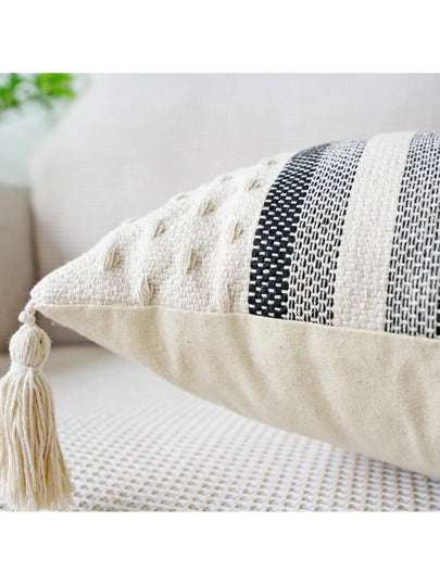 black and grey striped cushion with a white background, tassels on each corner and a textured feel on the bottom and top close up