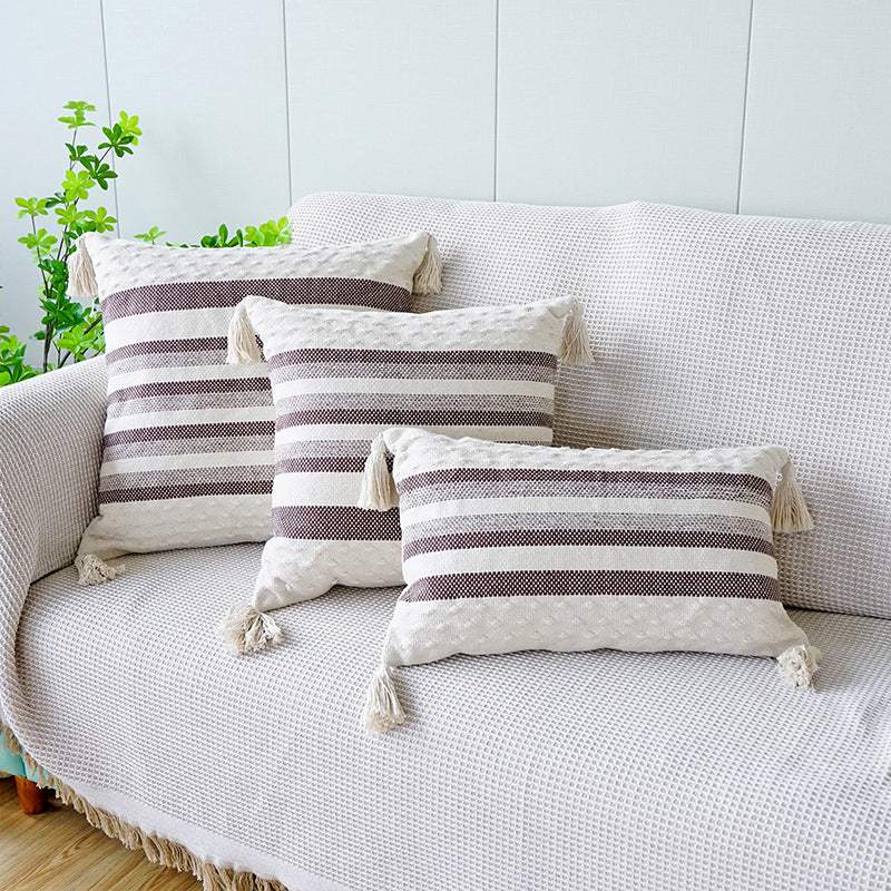 Two shades of coffee striped cushion with a white background, tassels on each corner and a textured feel on the bottom and top