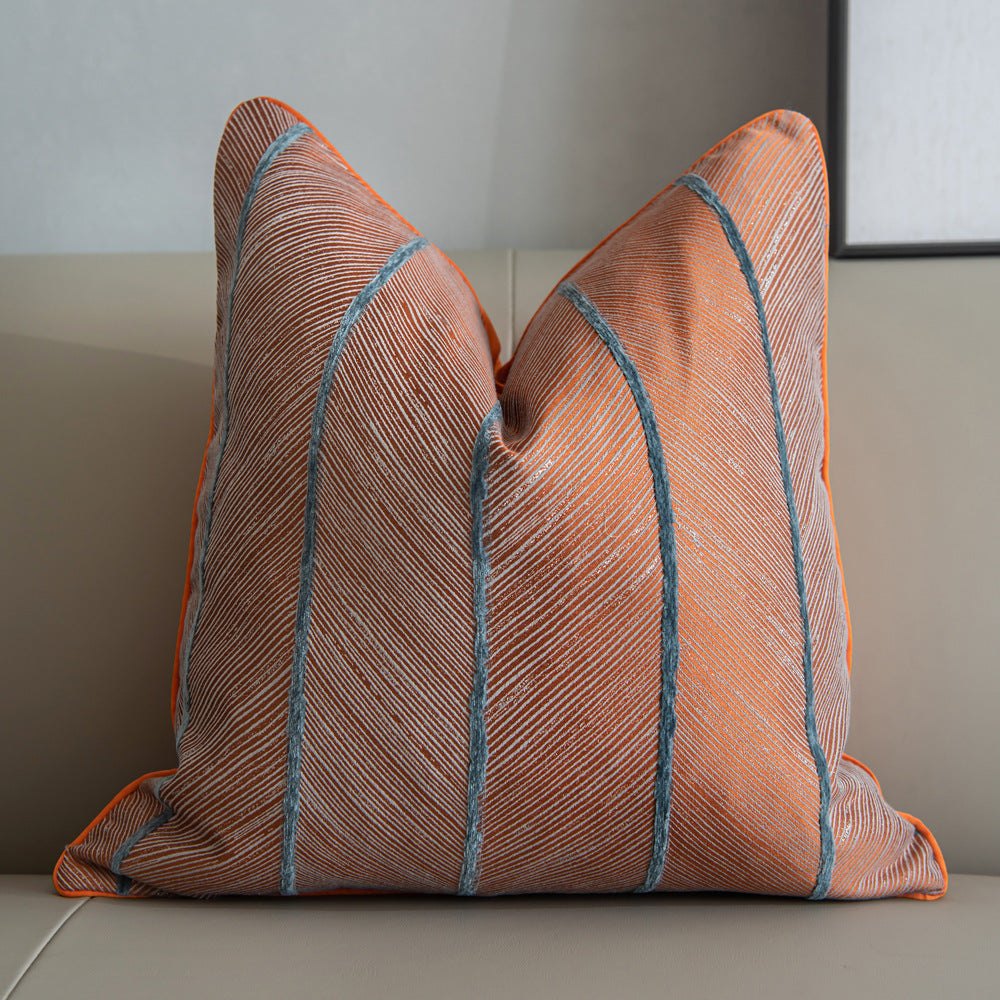 Orange with blue stripes running down this affordable luxury cushion with leaf rugged pattern on the cushion